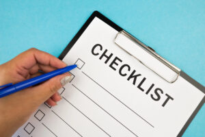 A hand holding a pen filling a checklist on a clipboard