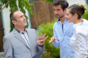 A landlord holding a folder talking to a couple tenant
