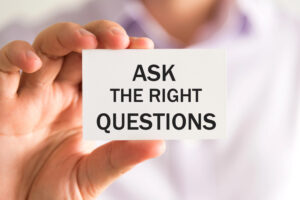 A hand holding a paper written 'ask the right questions'