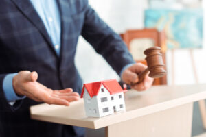 a man standing behind a podium holding a gavel pointing at a dummy house